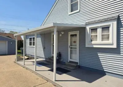 Side view of a Michigan home with blue siding and a white aluminum awning built by Wayne Craft
