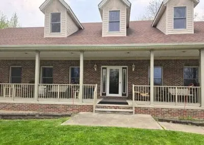 Wide front porch of a Michigan brick home with beige aluminum railings built by Wayne Craft