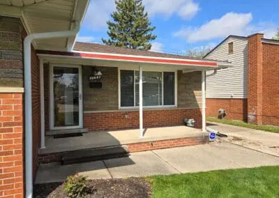 Michigan brick home with white aluminum awning accented with a red trim built by Wayne Craft