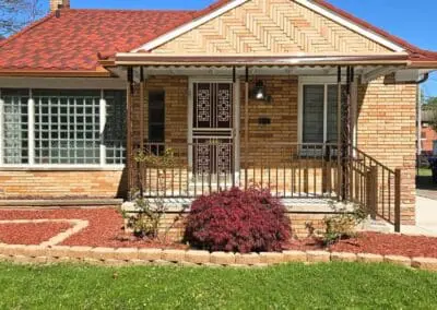 Front view of a Michigan brick home featuring a brown aluminum awning and railing built by Wayne Craft