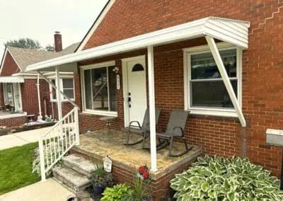 Red brick residential home with a white awning and porch railing built by Wayne Craft