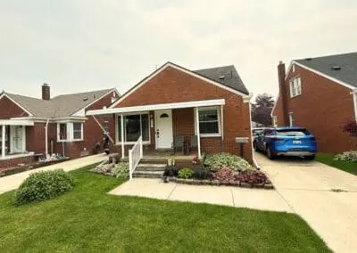 Red brick residential home with a white awning and porch railing built by Wayne Craft