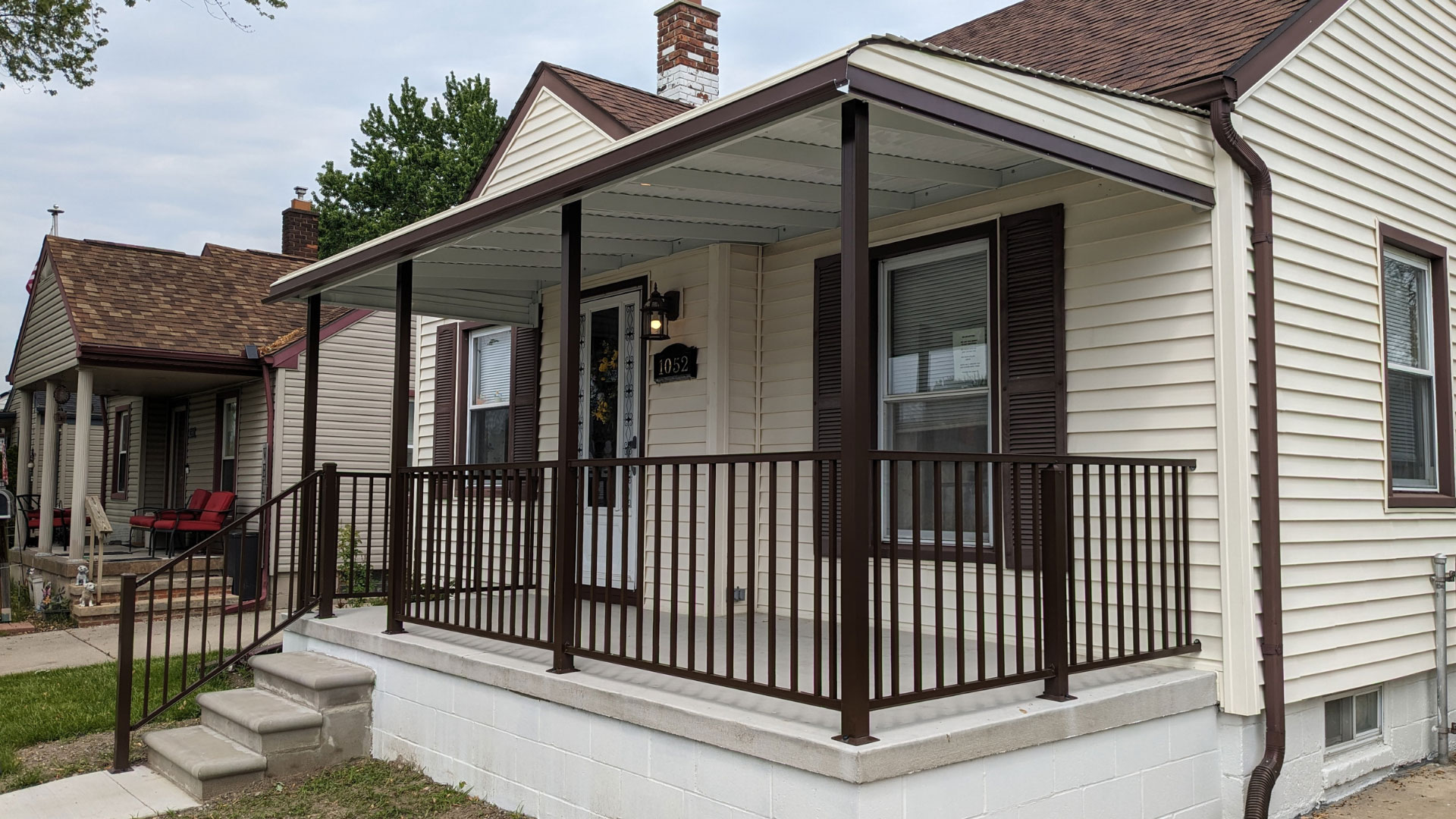 Custom dark brown aluminum railing on a modern front porch with stone stairs and pathway