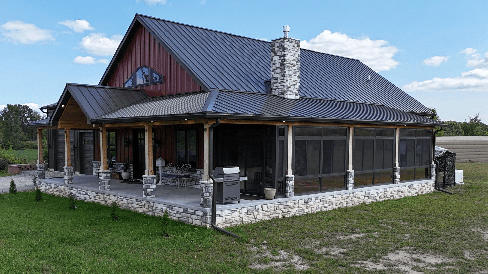 Custom four-season sunroom enclosure with screened patio and stone columns on a modern home exterior.